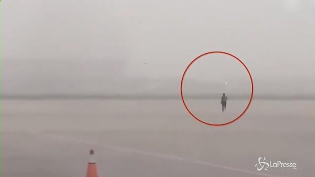 Pechino, il forte vento mette in difficoltà un passeggero all’imbarco