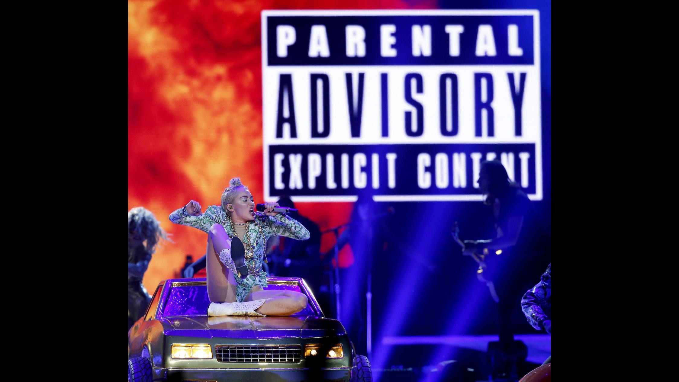 Miley Cyrus in tour: maxilingua e gambe spalancate sul cofano