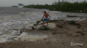 Dorian, l’uragano non spaventa il surfista: cavalca le onde sotto un cielo minaccioso