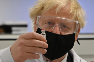 Il primo ministro Boris Johnson osserva i lavoratori che eseguono test di qualità del processo di produzione dei vaccini Covid-19