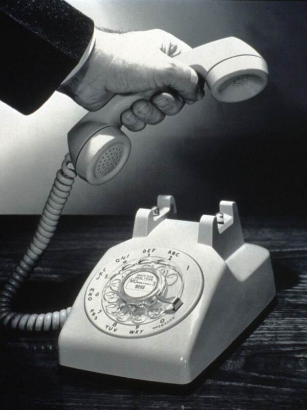 PARTICOLARE DI MANO CHE ALZA LA CORNETTA DEL TELEFONO