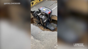 Piogge torrenziali in Giappone: un veicolo incastrato in un enorme buco nell’asfalto