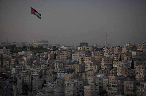 BLOCKY CREAM COLORED BUILDINGS AND A MOSQUE AND THE JORDAN FLAG.