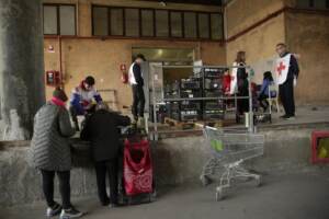 Povertà, alcune famiglie si recano alla sede della Croce Rossa per ricevere i pacchi degli aiuti alimentari