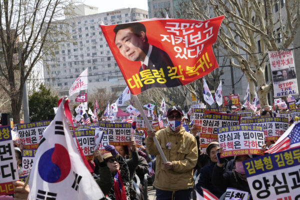 La faccia del presidente sudcoreano destituito Yoon Suk Yeol su una bandiera in una manifestazione a Seul dopo il suo impeachment