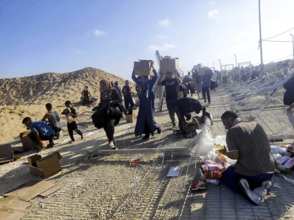 Palestinesi con in spalla pacchi di aiuti umanitari nella Striscia di Gaza