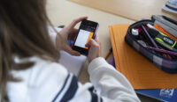 Una studentessa usa un cellulare a scuola. Una circolare del ministro Valditara ha vietato gli smartphone alle superiori in Italia