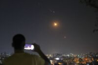 Un uomo osserva e filma con il cellulare i missili dall'Iran verso Israele