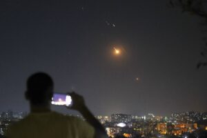 Un uomo osserva e filma con il cellulare i missili dall'Iran verso Israele