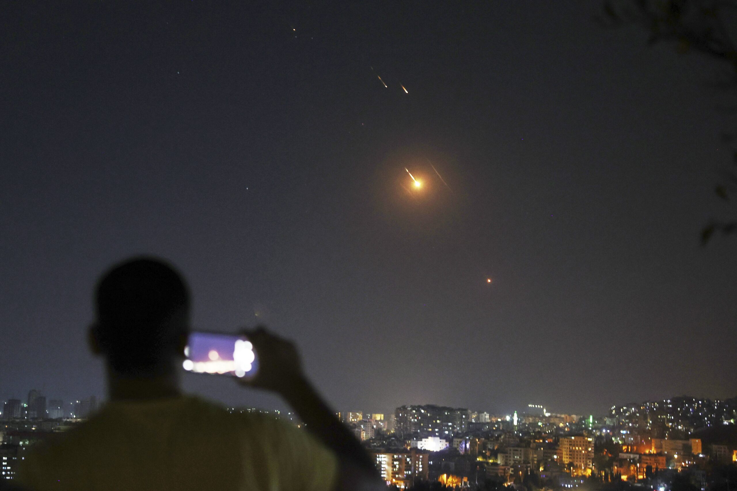 Un uomo osserva e filma con il cellulare i missili dall'Iran verso Israele