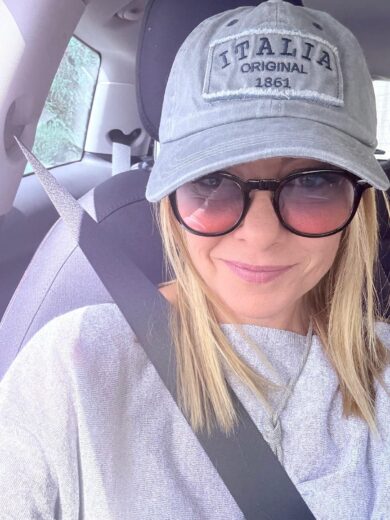 Giorgia Meloni augura “Buona domenica” con un selfie in auto e cappellino “Italia original 1861”