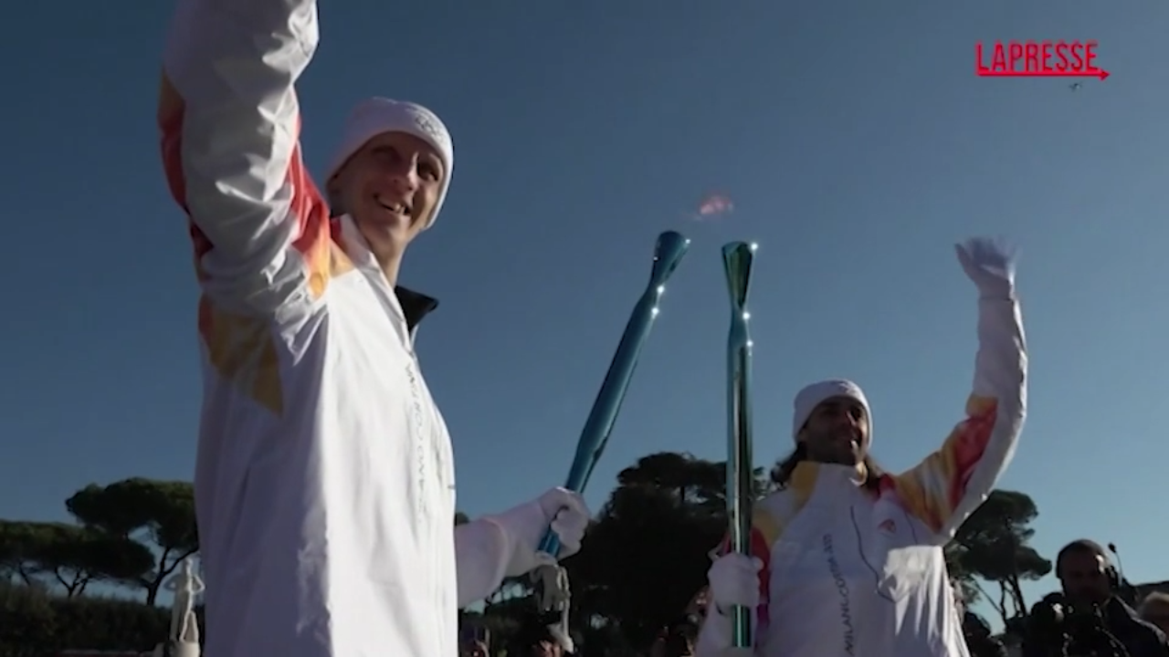 Milano Cortina 2026, Polonara tedoforo accompagna la torcia fuori dallo Stadio dei Marmi Milano Cortina 2026, Polonara tedoforo accompagna la torcia fuori dallo Stadio dei Marmi