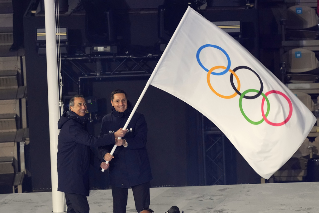 Il sindaco di Milano Giuseppe Sala e quello di Cortina d’Ampezzo Gianluca Lorenzi sventolano la bandiera olimpica (AP Photo/Antonio Calanni)
