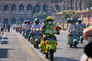 Una lunga fila di appassionati della Vespa lungo via dei Fori Imperiali. Sullo sfondo, il Colosseo. (AP Photo/Alessandra Tarantino)