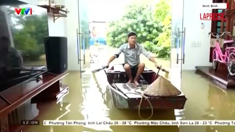 Vietnam, case sommerse a causa delle inondazioni: un uomo entra in salotto con la canoa