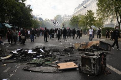 Alcuni manifestanti passano accanto a rifiuti bruciati dopo una manifestazione contro la carenza di risorse nelle scuole, a Parigi (Foto AP/Teresa Suarez)